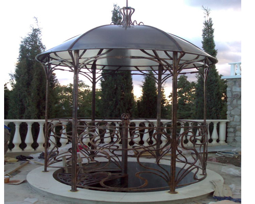 Фото 9 – Шестигранная беседка с коваными элементами и крышей из поликарбоната