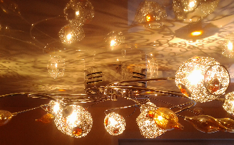 Фото 1 – Сочетание хромированного каркаса люстры, стеклянных элементов и глянцевого потолка